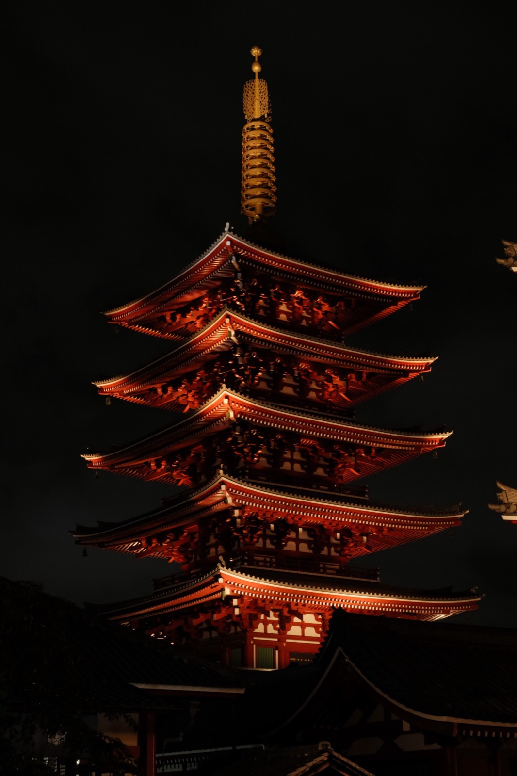 La pagoda de cinco pisos de Senso-ji iluminada de rojo de noche contra un cielo negro